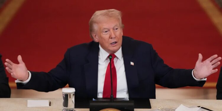 President Donald Trump speaking at a roundtable discussion on college sports, with his arms outstretched.