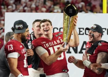 Fernando Mendoza and other football players celebrating with a trophy.