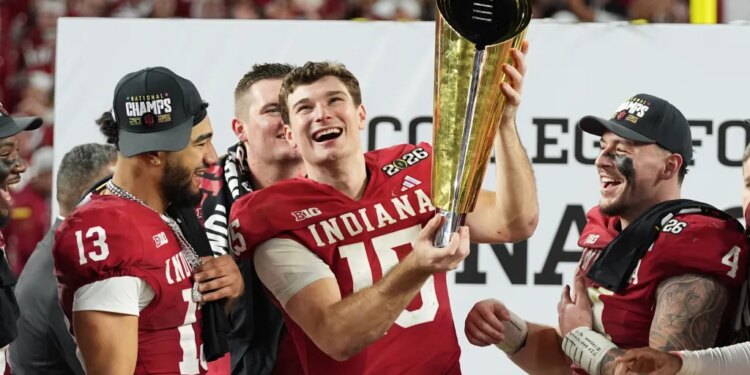 Fernando Mendoza and other football players celebrating with a trophy.