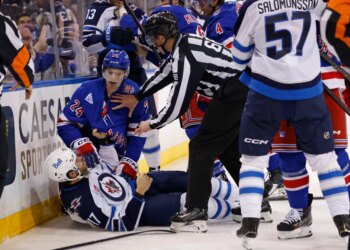 New York Rangers player Tye Kartye and Winnipeg Jets player Adam Lowry scuffle on the ice, separated by a referee.