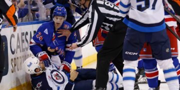 New York Rangers player Tye Kartye and Winnipeg Jets player Adam Lowry scuffle on the ice, separated by a referee.