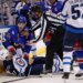 New York Rangers player Tye Kartye and Winnipeg Jets player Adam Lowry scuffle on the ice, separated by a referee.