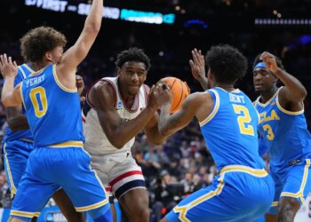 UConn's Tarris Reed Jr. holding the basketball, surrounded by UCLA players Trent Perry, Donovan Dent, and Eric Dailey Jr.