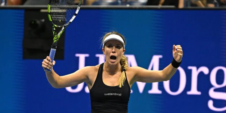 A female tennis player in a black top and light purple skirt, holding a tennis racket and celebrating a point with both arms raised.