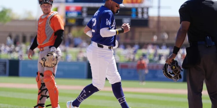 Los Angeles Dodgers player Miguel Rojas scoring a run as San Francisco Giants catcher Patrick Bailey and home plate umpire Alan Porter look on.