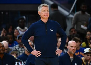 Golden State Warriors head coach Steve Kerr stands with his hands on his hips while looking at the court.