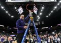 A Northern Iowa Panthers basketball coach cutting down the net after winning the Missouri Valley Conference Tournament.