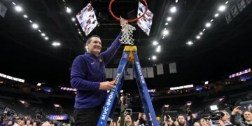 A Northern Iowa Panthers basketball coach cutting down the net after winning the Missouri Valley Conference Tournament.