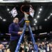 A Northern Iowa Panthers basketball coach cutting down the net after winning the Missouri Valley Conference Tournament.
