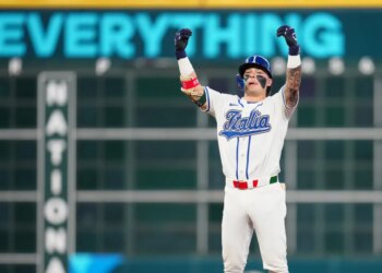 Andrew Fischer in an "Italia" jersey with his arms raised in celebration after hitting a two-run double.