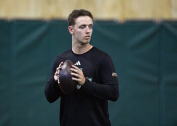 Miami quarterback Carson Beck holds a football, looking to his right.
