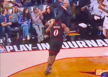 A basketball player high-fiving fans in the stands.