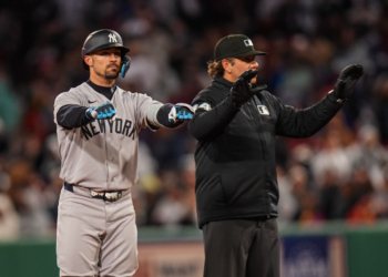 New York Yankees left fielder Randal Grichuk (34) after hitting a double, with an umpire beside him.