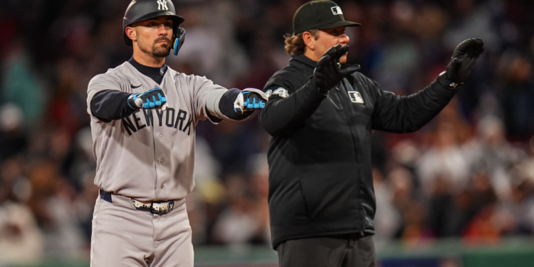 New York Yankees left fielder Randal Grichuk (34) after hitting a double, with an umpire beside him.