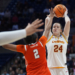 An Iowa State player in a white and gold jersey shoots a basketball while a Syracuse player in an orange jersey defends.