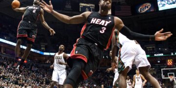 Miami Heat's Dwyane Wade reacting as teammate LeBron James goes up for a dunk against the Milwaukee Bucks.