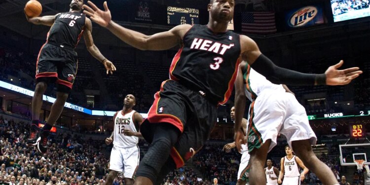 Miami Heat's Dwyane Wade reacting as teammate LeBron James goes up for a dunk against the Milwaukee Bucks.