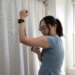 Senior reviewer Victoria Song applying a CGM to the bottom fo her arm in front of a curtain