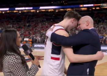 A basketball player and coach embrace on the court during an interview, with a "FINAL FOUR" logo visible in the background.