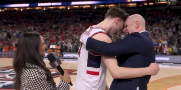 A basketball player and coach embrace on the court during an interview, with a "FINAL FOUR" logo visible in the background.