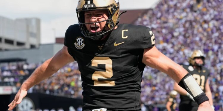 A Vanderbilt football player, wearing number 2, in a black and gold uniform, cheers with his arms outstretched.
