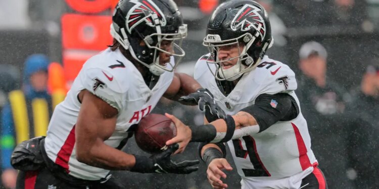 Atlanta Falcons #9 Desmond Ridder hands the ball to #7 Bijan Robinson.