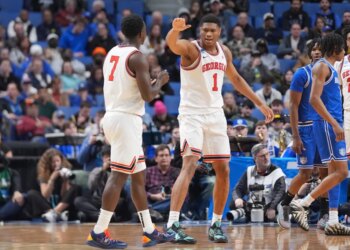 Two basketball players from Georgia, number 1 and number 7, talking on the court.
