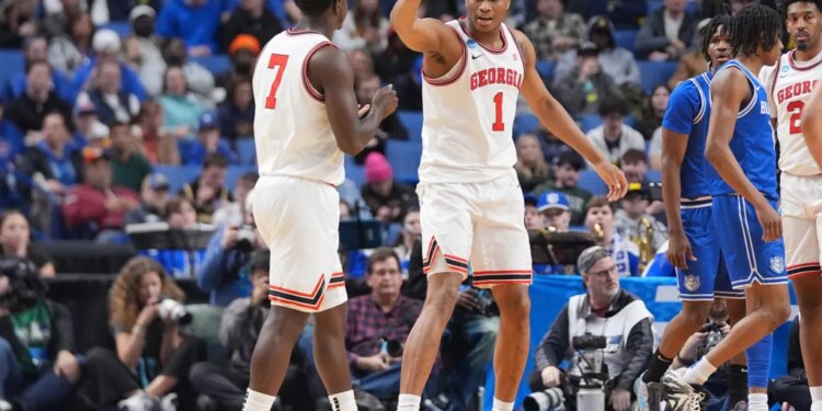Two basketball players from Georgia, number 1 and number 7, talking on the court.