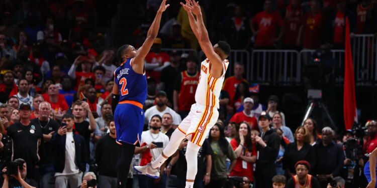 Basketball players CJ McCollum and Miles McBride jump for the ball during an NBA Playoffs game.