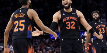 A smiling Karl-Anthony Towns celebrates with Mikal Bridges during the Knicks' Game 5 blowout win over the Hawks.