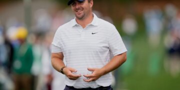 Golfer Scott Stallings smiling and holding a golf ball.