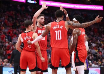 Houston Rockets players Alperen Sengun, Jabari Smith Jr., Amen Thompson, and another teammate huddle together.