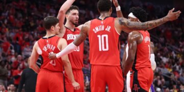 Houston Rockets players Alperen Sengun, Jabari Smith Jr., Amen Thompson, and another teammate huddle together.