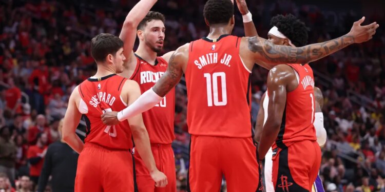 Houston Rockets players Alperen Sengun, Jabari Smith Jr., Amen Thompson, and another teammate huddle together.