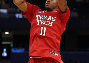 A Texas Tech basketball player in a red jersey with number 11 shoots a basketball.