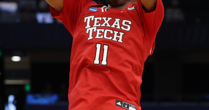 A Texas Tech basketball player in a red jersey with number 11 shoots a basketball.