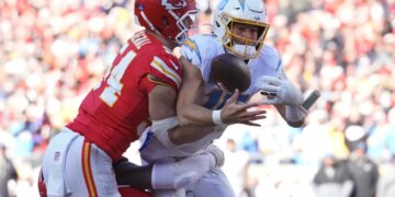 Kansas City Chiefs linebacker Leo Chenal hitting Los Angeles Chargers quarterback Justin Herbert during a game.