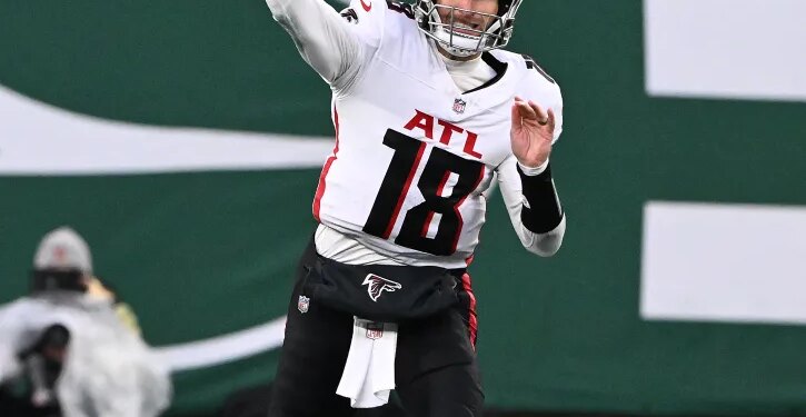 A quarterback in a white and black jersey with "ATL" and "18" visible, preparing to throw a football.