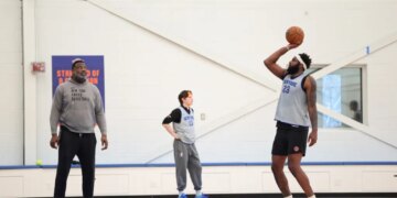 Mitchell Robinson #23 of the New York Knicks practices free throws, wearing a gray jersey and black shorts.