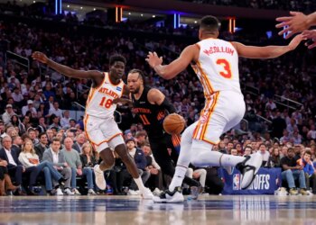 New York Knicks guard Jalen Brunson #11 drives to the basket between Atlanta Hawks forward Mouhamed Gueye #18 and Atlanta Hawks guard CJ McCollum #3.