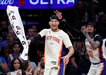 Basketball players Josh Hart and Jordan Clarkson of the New York Knicks react after scoring a three-point shot.