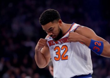 New York Knicks center Karl-Anthony Towns pulling his jersey over his chest.