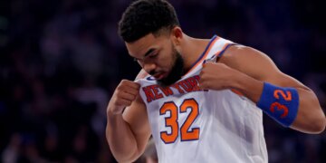 New York Knicks center Karl-Anthony Towns pulling his jersey over his chest.