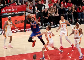 New York Knicks center Karl-Anthony Towns (32) goes up for a shot in front of multiple Atlanta Hawks players.