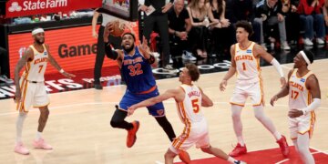 New York Knicks center Karl-Anthony Towns (32) goes up for a shot in front of multiple Atlanta Hawks players.