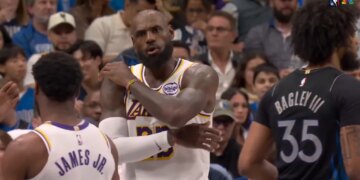 LeBron James, in a Lakers jersey, gestures with his arms crossed while talking to his son, Bronny James Jr. in a Lakers jersey.
