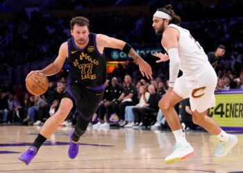 Luka Doncic drives past Max Strus during an NBA game.