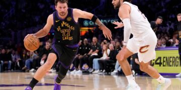 Luka Doncic drives past Max Strus during an NBA game.