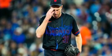 Toronto Blue Jays pitcher Max Scherzer in a black jersey and cap, touching his head.