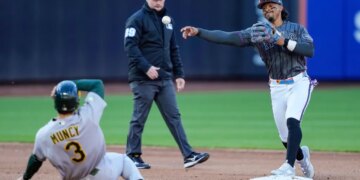 Mets shortstop Francisco Lindor, right, throws to first base after a force out against Athletics' Max Muncy (3) at second base during the fifth inning of a baseball game, Saturday, April 11, 2026.